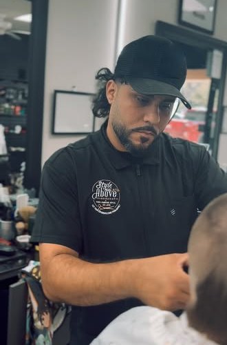 A Style From Above barber in a shop logo polo lining up a client's cut